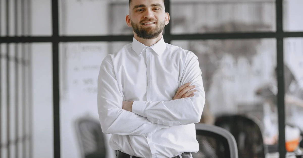 Retrato de un hombre de negocios sonriente que se encuentra de pie con confianza en un entorno de oficina moderna.